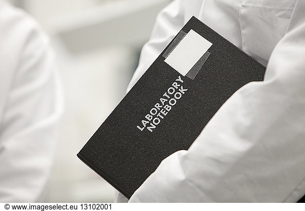 Mid-section of scientist holding note pad