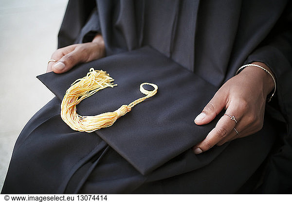 Mid-section of woman holding mortarboard
