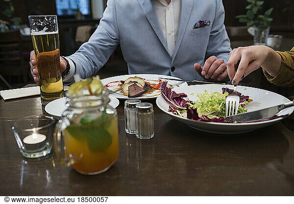 Mid section of young couple eating at restaurant