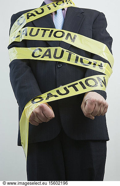 Mid section view of a businessman wrapped in a Caution tape