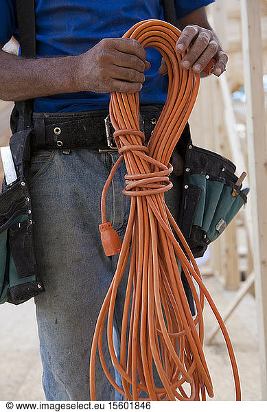 Mid section view of a carpenter holding coiled power cord