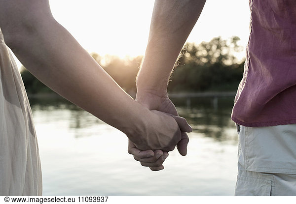 Mid section view of a couple in love holding hands during sunset  Bavaria  Germany