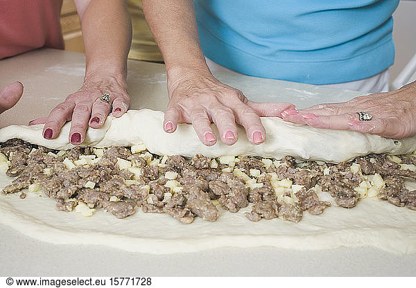 Mid section view of two women making rolled sausage bread