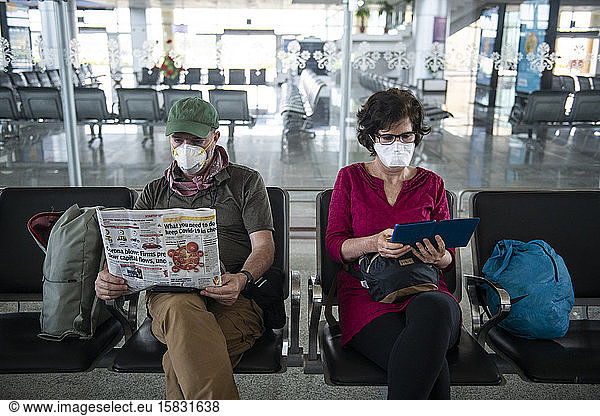 Middle aged couple wear face masks due to the Coronavirus pandemic while waiting at a deserted airport in Khajuraho  Madhya Pradesh  India.