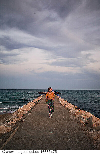Middle-aged woman walks on a catwalk on the coast