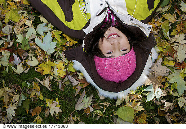 Middle Eastern Girl Lying In Autumn Leaves Outside Esl School; Guelph Ontario Kanada
