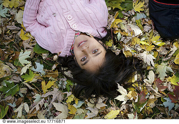 Middle Eastern Girl Lying In Autumn Leaves Outside Esl School; Guelph Ontario Kanada