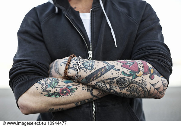 Midsection of a tattooed man with arms crossed