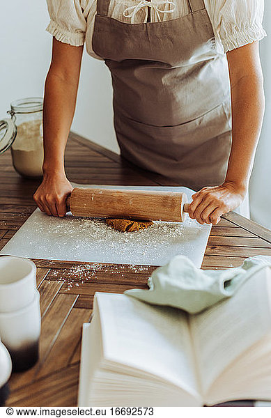 Midsection of a woman rolling dough for cookies at domestic kitchen