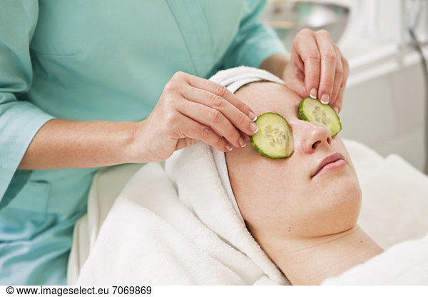 Midsection of beautician giving a beauty treatment to young woman in spa