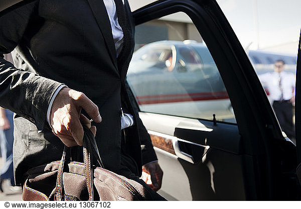 Midsection of businessman getting in car