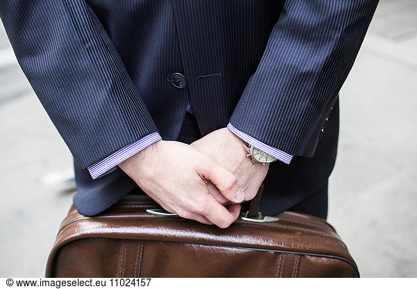 Midsection of businessman holding briefcase standing in city