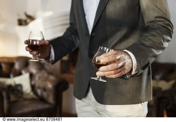 Midsection of businessman holding wineglasses at restaurant