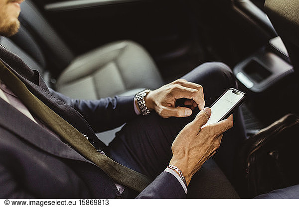 Midsection of businessman using device screen while sitting in car
