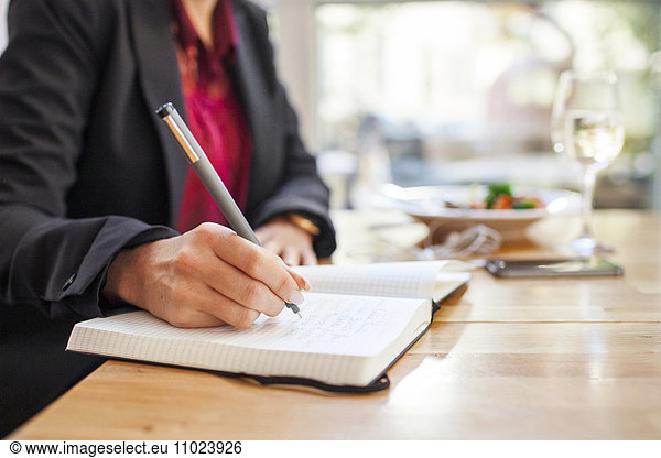 Midsection of businesswoman writing in book