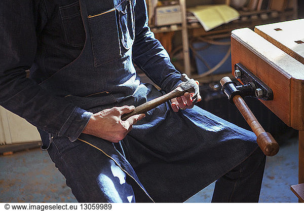 Midsection of carpenter holding hammer at workshop
