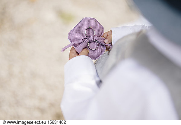 Midsection of child holding wedding rings while standing outdoors