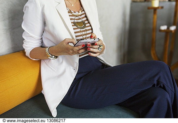 Midsection of creative businesswoman using smart phone in hotel lobby