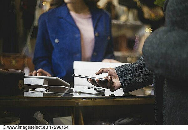 Midsection of customer doing contactless payment at clothing store