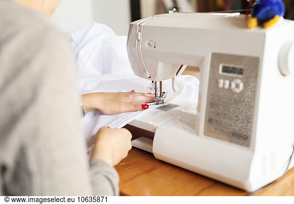 Midsection of design professional using sewing machine at table