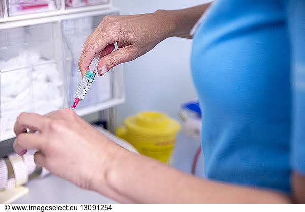 Midsection of female doctor holding syringe while standing in hospital