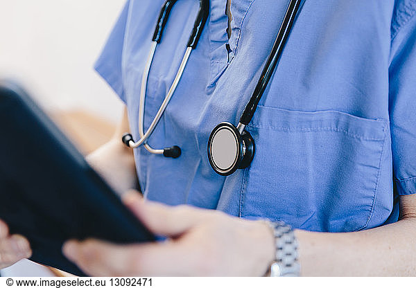 Midsection of female doctor using tablet computer in hospital