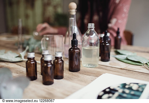 Midsection of female entrepreneur preparing perfume at table in workshop