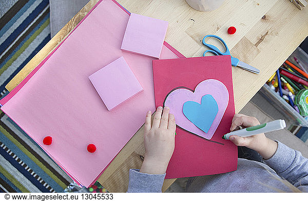 Midsection of girl making Valentine card at home