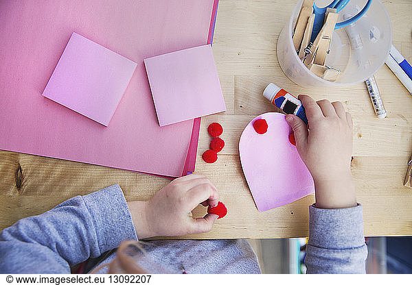Midsection of girl making valentine greeting card at home