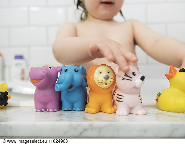 Midsection of girl playing with rubber toys in bathtub