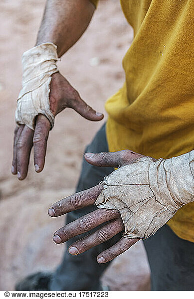 Midsection of male mountaineer with bandages wrapped on messy hands