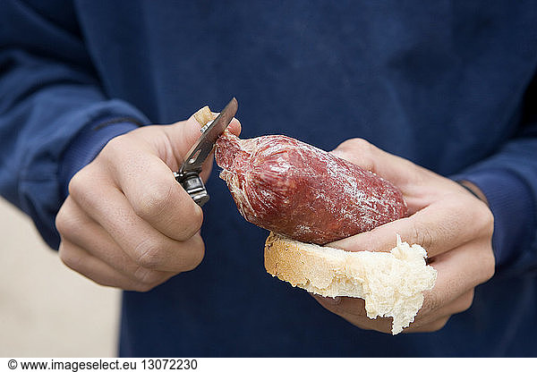 Midsection of man cutting meat