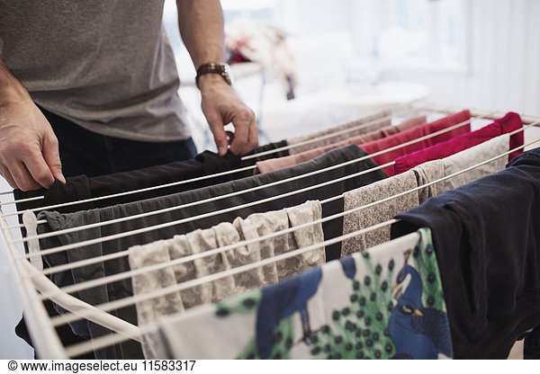 Midsection of man drying clothes on rack at home