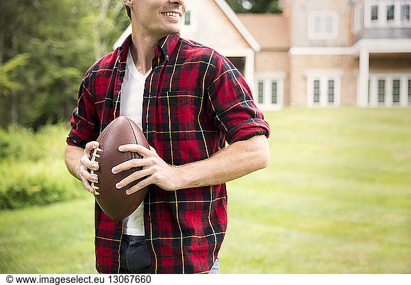 Midsection of man holding football