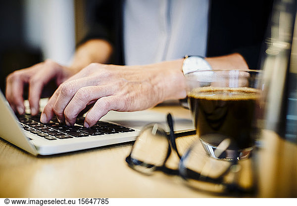 Midsection of mature lawyer using laptop at desk in office