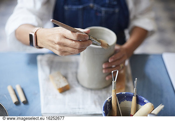 Midsection of mature woman learning pottery in art class