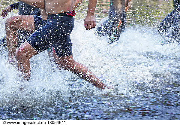 Midsection of men running in lake