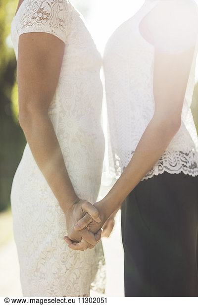 Midsection of newlywed lesbian couple holding hands