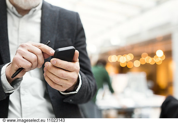 Midsection of senior businessman using mobile phone in office