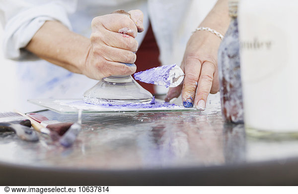 Midsection of senior female painter using printing block in studio