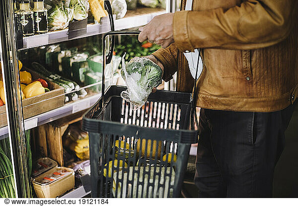 Midsection of senior man buying organic broccoli at grocery store