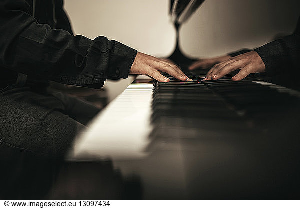 Midsection of teenage boy playing piano