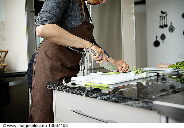Midsection of woman cutting scallion