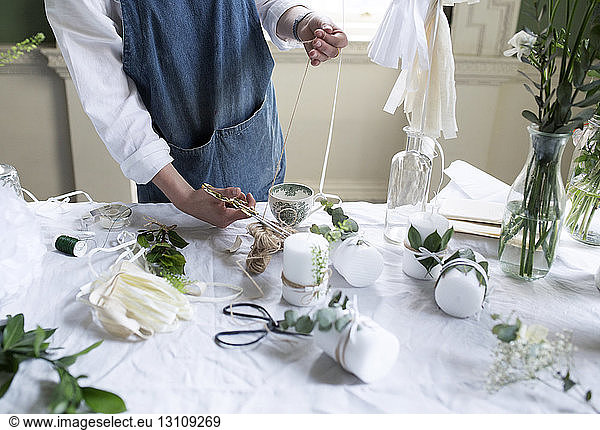 Midsection of woman cutting thread at table in workshop