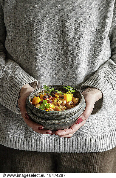 Midsection of woman holding bowl of North African stew with pumpkin  chickpeas  lentils  dates and cilantro