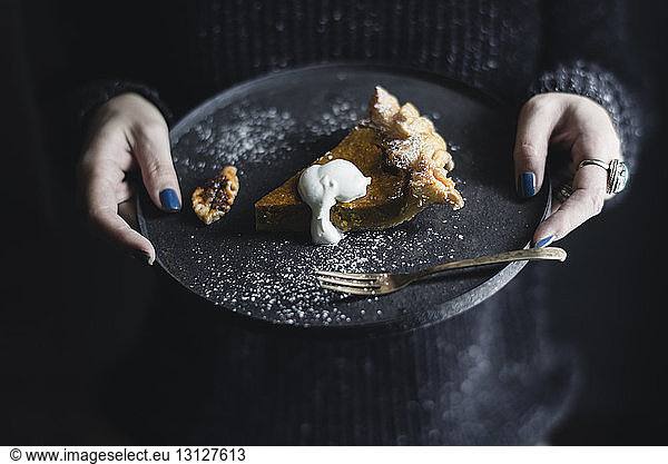 Midsection of woman holding pumpkin pie in plate