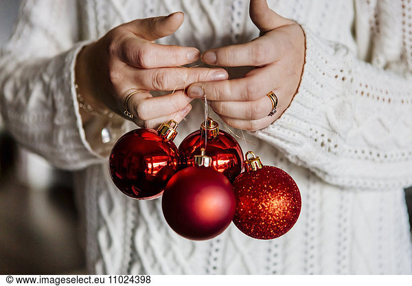 Midsection of woman holding red Christmas baubles