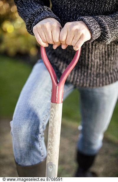 Midsection of woman holding shovel at garden