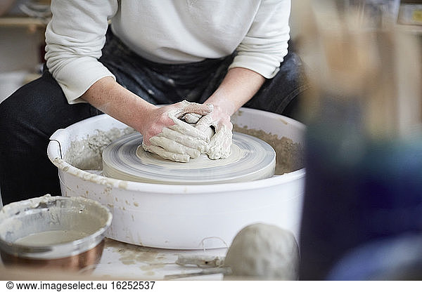 Midsection of woman molding pot in pottery class