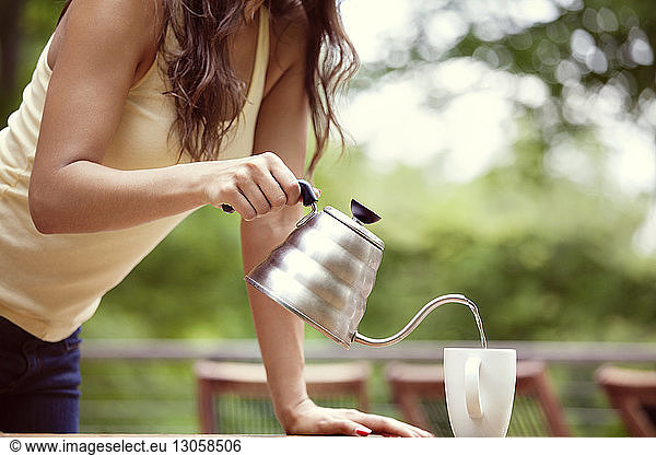 Midsection of woman pouring drink in mug